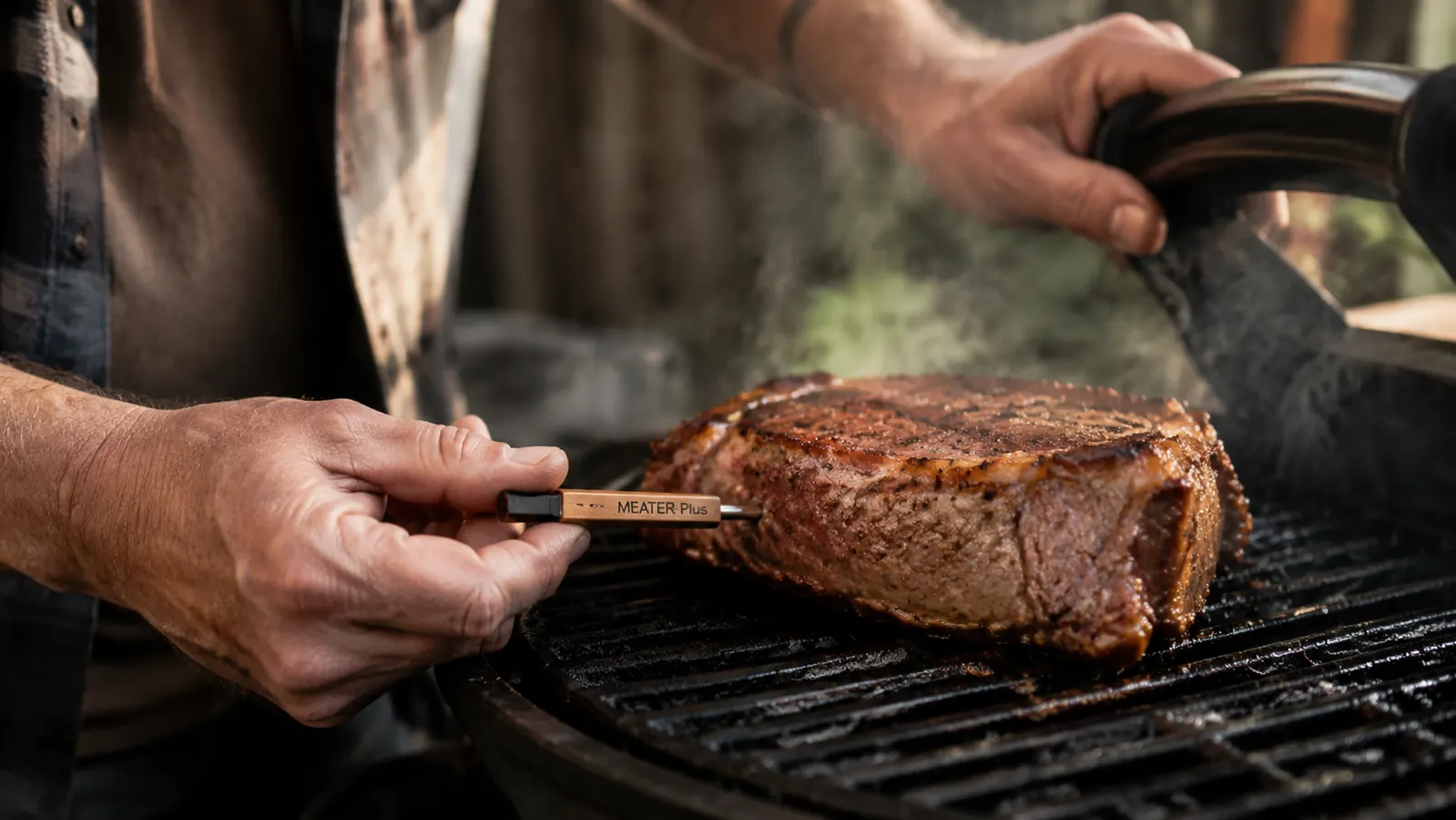 Hand inserting a wireless meat thermometer probe into a thick steak on a grill grate