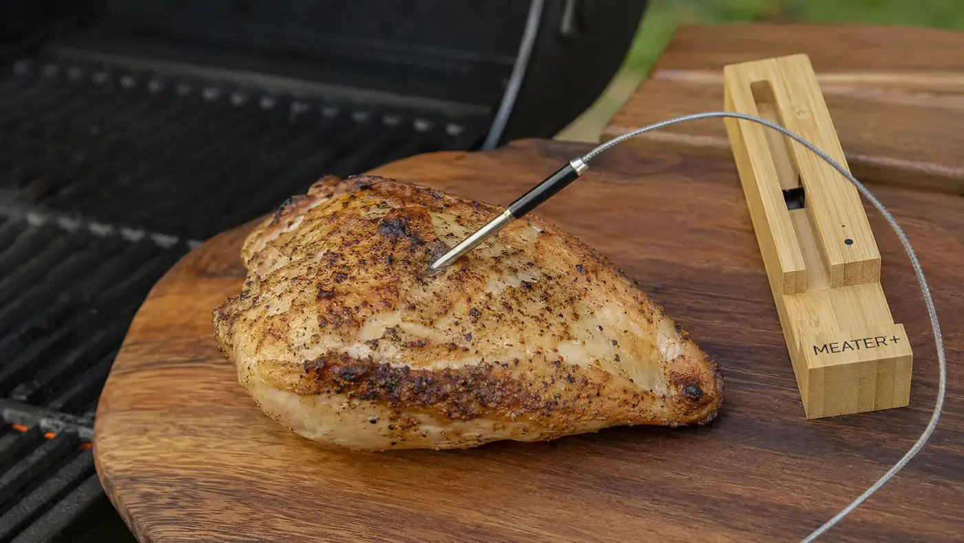Wireless meat thermometer probe inserted into a chicken breast resting on a cutting board