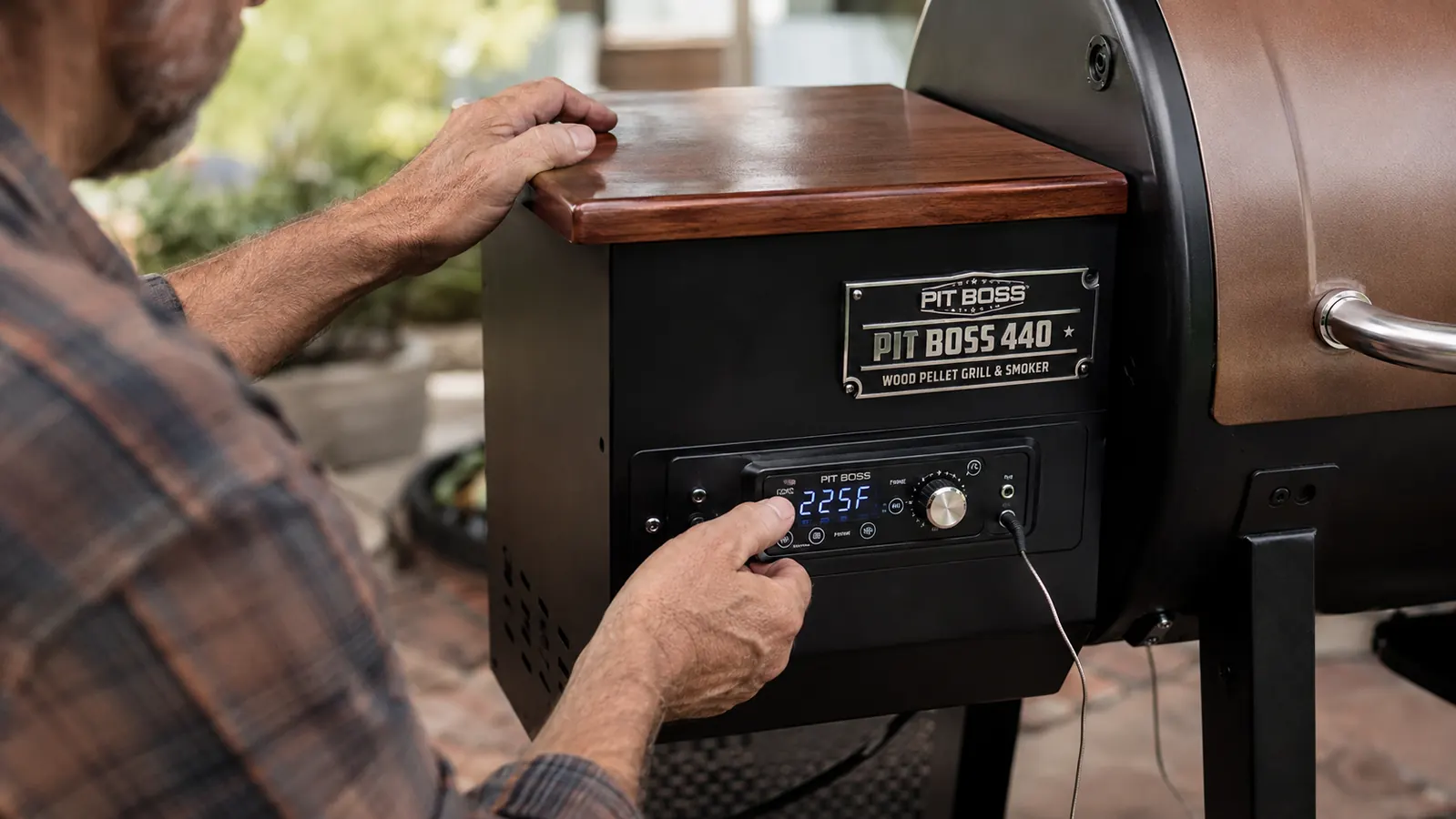 Hand adjusting the LED digital controller on the Pit Boss 440 Mahogany Series pellet grill